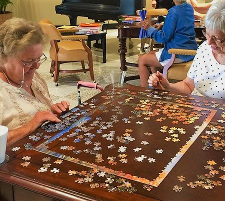 two senior women are doing a puzzle